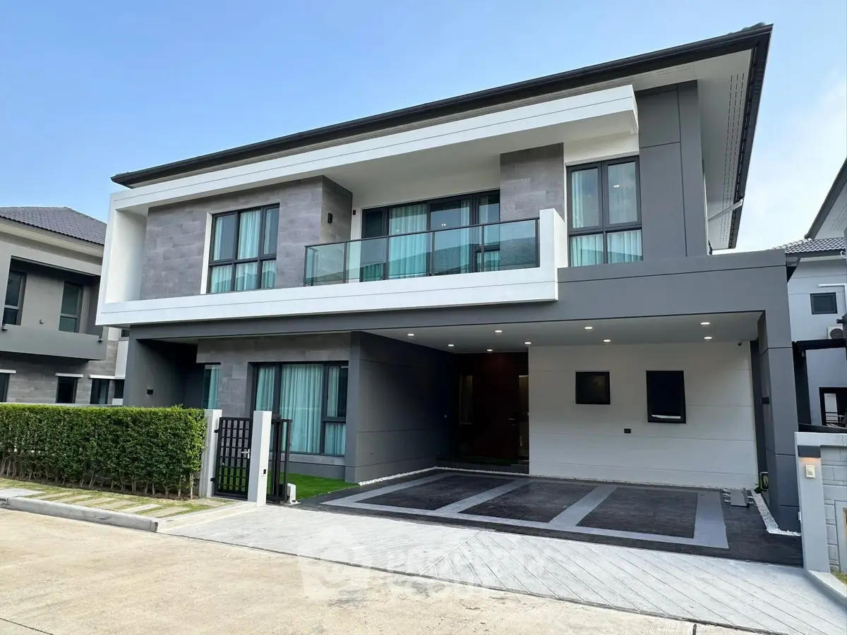 Modern two-story house with sleek design and spacious driveway in a suburban neighborhood.