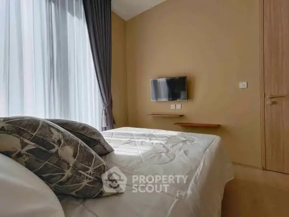 Cozy bedroom with modern decor and wall-mounted TV, perfect for relaxation.