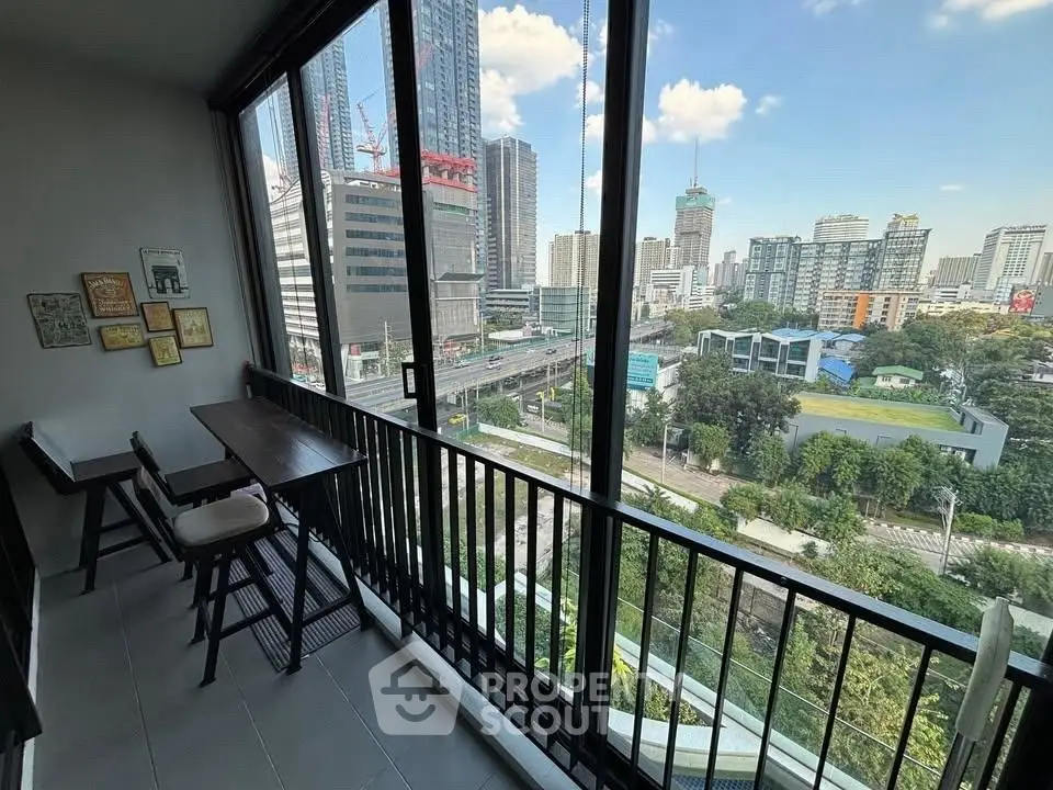 Stunning city view from modern balcony with seating area in high-rise apartment.