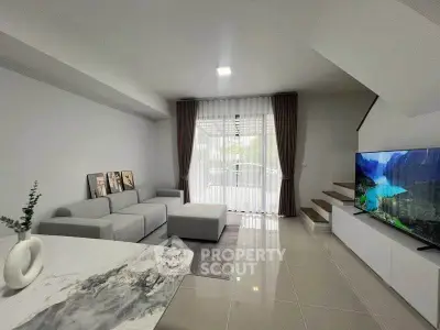 Modern living room with sleek design, large TV, and natural light from balcony.