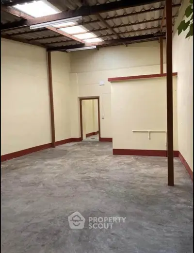 Spacious industrial-style room with high ceilings and concrete floor, ideal for storage or workshop.