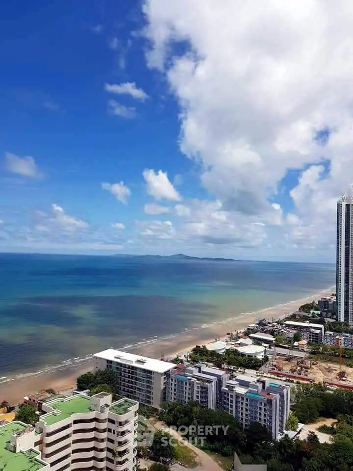 Stunning beachfront view from high-rise building with clear blue skies and ocean horizon.