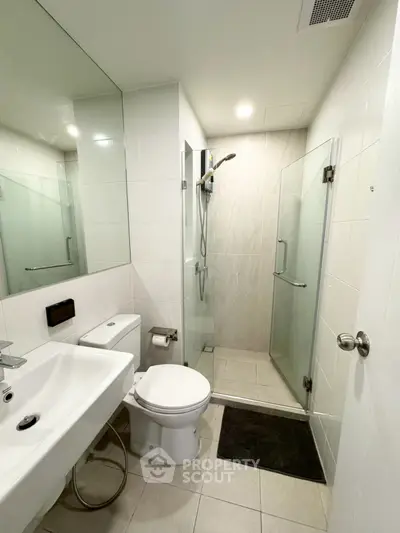 Modern bathroom with glass shower and sleek white fixtures.