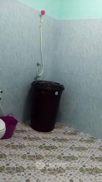 Simple bathroom with tiled walls and floor, featuring a shower and a large water container.