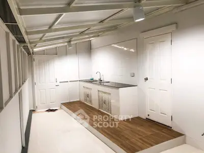 Modern minimalist kitchen with sleek white cabinetry and elevated wooden flooring