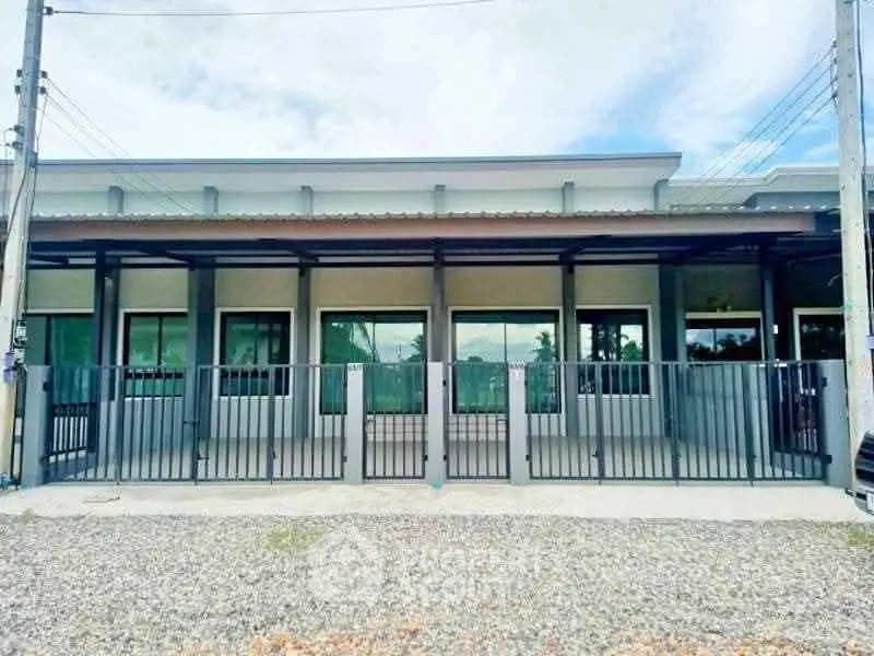 Modern single-story building with gated entrance and large windows, ideal for commercial or residential use.