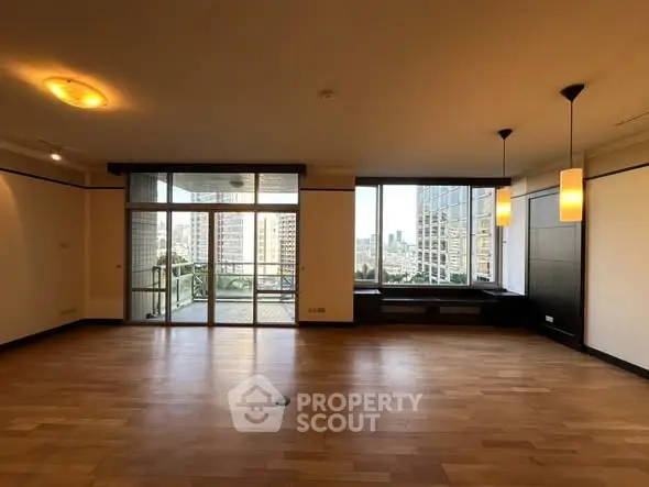 Spacious living room with large windows and city view, featuring elegant lighting and hardwood floors.