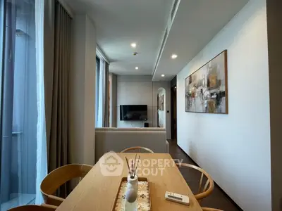 Modern living room with stylish decor and natural light, featuring a wall-mounted TV and elegant dining area.