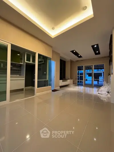 Spacious modern living room with sleek lighting and glossy tiled floors, perfect for contemporary living.