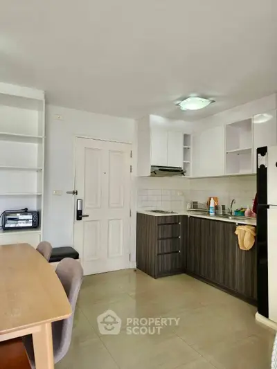 Modern kitchen with sleek cabinetry and dining area in a cozy apartment