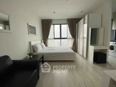 Modern bedroom with large window and washing machine, featuring sleek furniture and neutral tones.