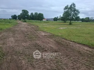 Expansive plot of land with potential for development, surrounded by greenery and a clear sky.