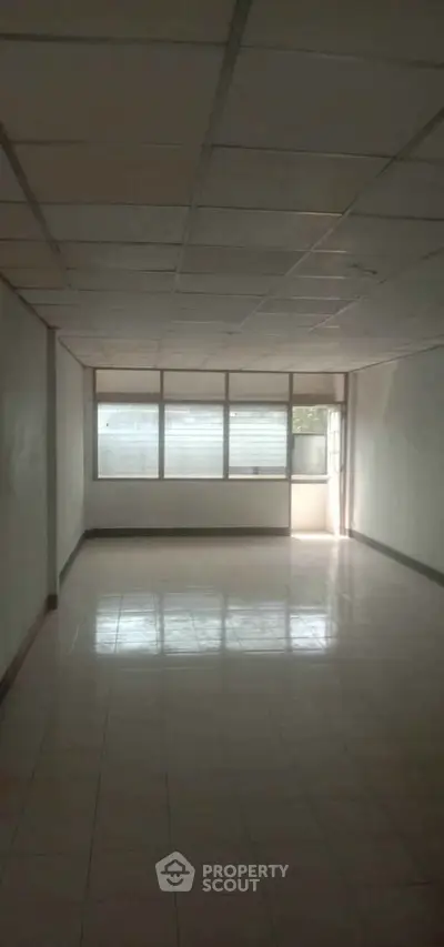 Spacious empty room with large windows and tiled flooring, ideal for customization.