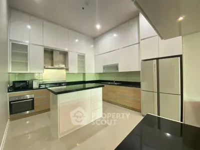 Modern kitchen with sleek cabinetry and island, featuring stainless steel appliances and glossy countertops.