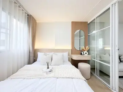 Modern bedroom with stylish decor and natural light, featuring a cozy bed and elegant furnishings.