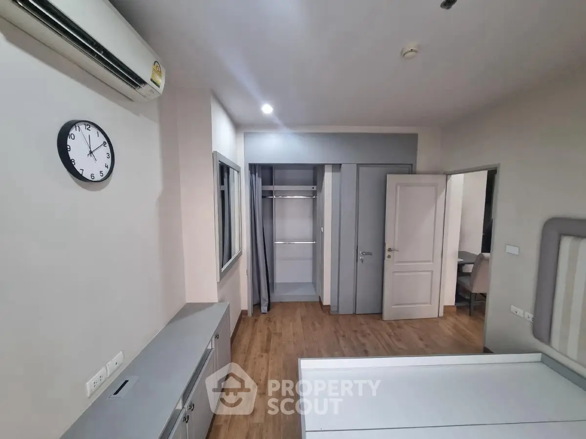 Modern bedroom with open closet and air conditioning, featuring sleek design and wooden flooring.