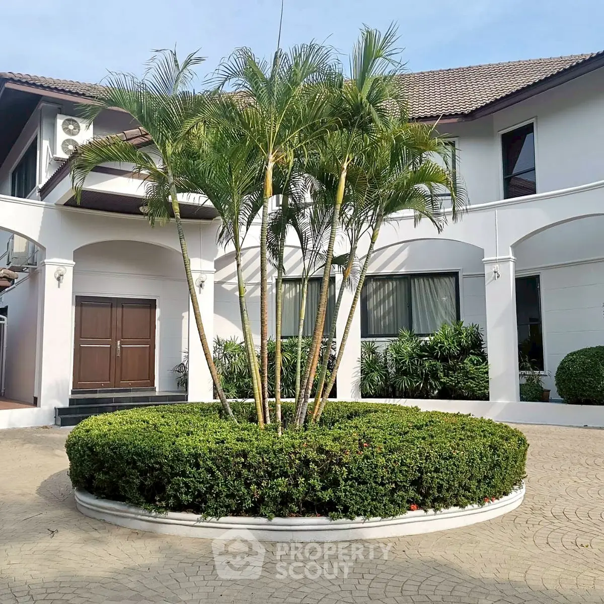 Elegant white villa with lush garden and circular driveway