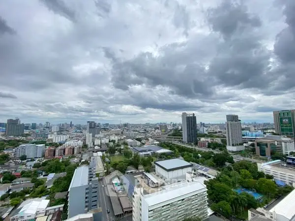 Stunning cityscape view from high-rise building showcasing urban skyline and cloudy sky.