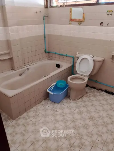 Vintage bathroom with classic bathtub and tiled walls, ideal for renovation enthusiasts.