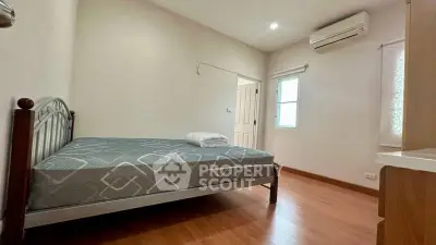 Cozy bedroom with wooden flooring and air conditioning, perfect for restful nights.