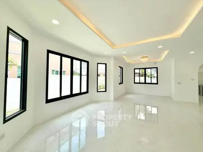 Spacious modern living room with large windows and elegant lighting in a luxury home.