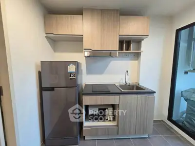 Modern compact kitchen with sleek cabinetry and stainless steel appliances in a stylish apartment.