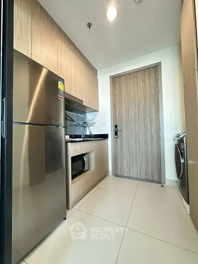 Modern kitchen with stainless steel appliances and sleek wooden cabinetry in a contemporary apartment.