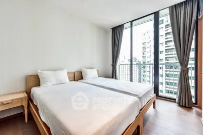 Spacious bedroom with twin beds and floor-to-ceiling windows offering city views.
