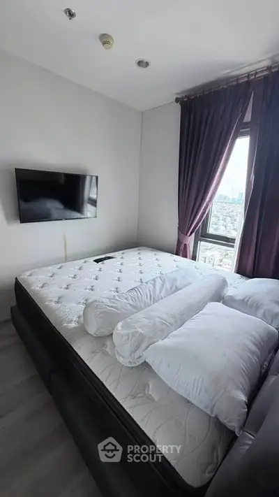 Spacious bedroom with city view, featuring a large bed and wall-mounted TV, perfect for relaxation.
