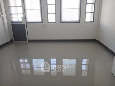 Spacious empty room with large windows and glossy tiled floor, perfect for customization.