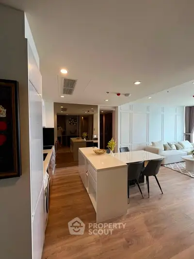 Spacious open-plan living room with modern kitchen and dining area, featuring elegant wood flooring.
