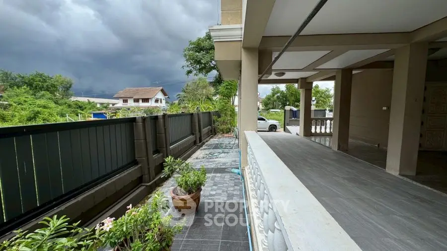 Spacious outdoor patio with lush greenery and stormy sky view