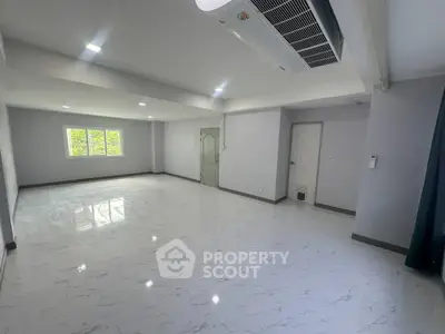 Spacious modern living room with sleek flooring and ample natural light.