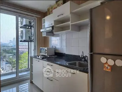 Modern kitchen with sleek cabinets, stainless steel fridge, and city view from window.