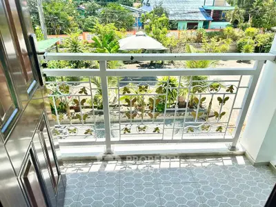 Charming balcony with decorative railing and lush garden view, perfect for relaxation.