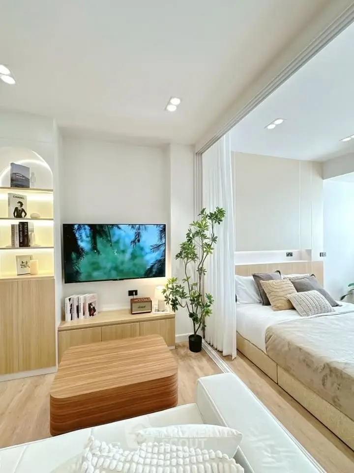 Modern open-plan living room with cozy bedroom, featuring stylish decor and natural light.