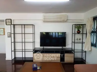 Spacious living room with modern TV setup and sleek shelving units.