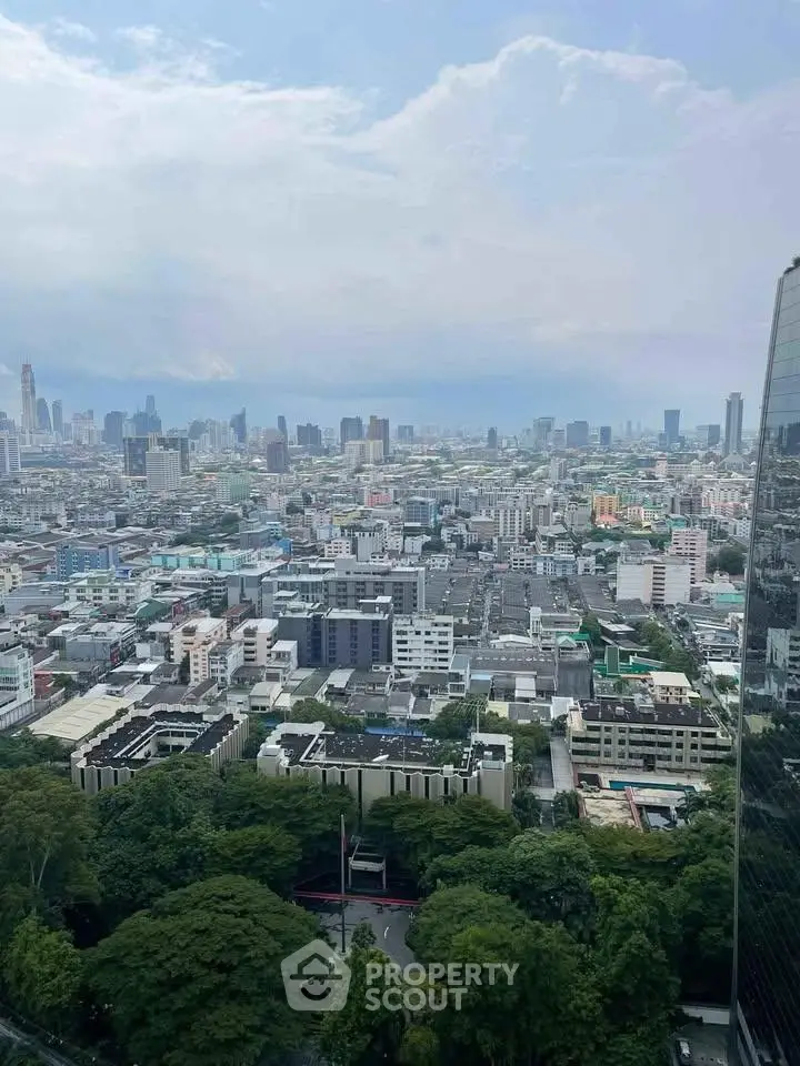 Stunning cityscape view from high-rise building showcasing urban skyline and lush greenery.
