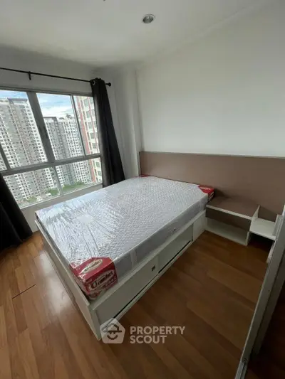 Modern bedroom with large window and wooden flooring in high-rise apartment.