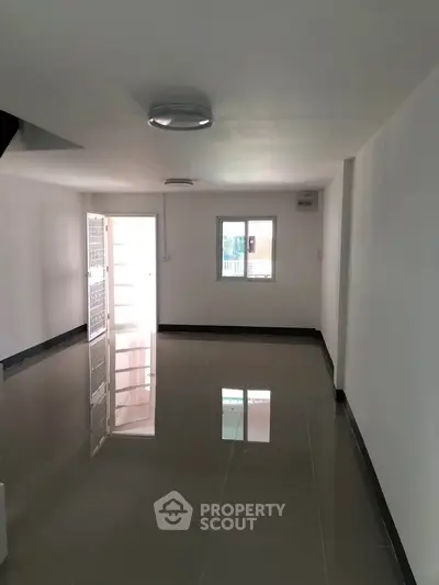 Spacious empty room with glossy tiled floor and natural light