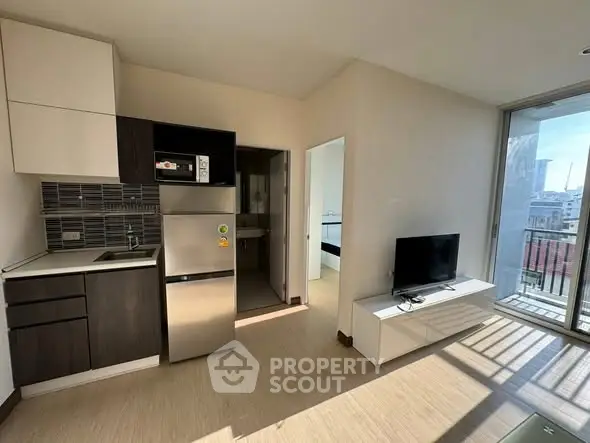 Modern apartment with open kitchen and balcony view, featuring sleek appliances and natural light.