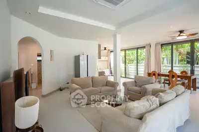 Spacious living room with cozy sofas and large windows offering garden views.