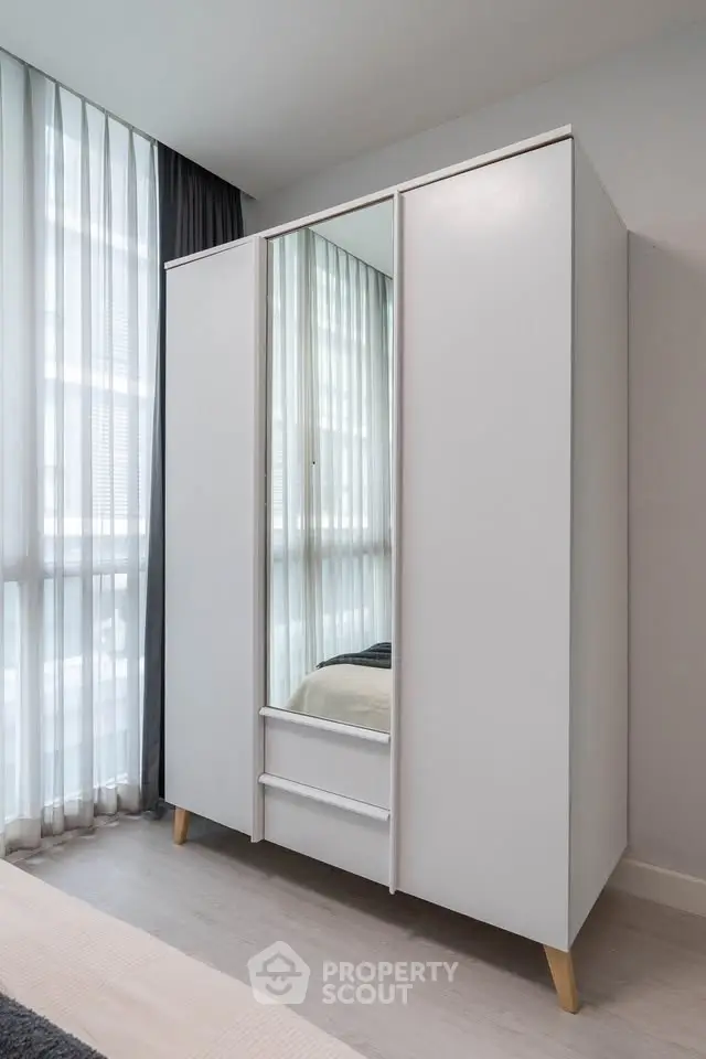 Modern bedroom with sleek white wardrobe and large windows for natural light.