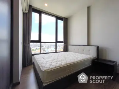 Modern bedroom with large windows and city view, featuring a comfortable bed and sleek design.