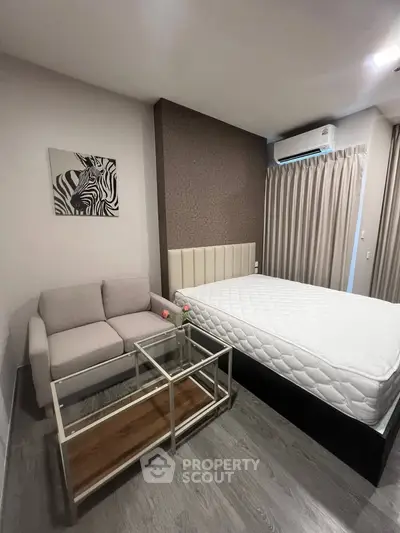 Modern bedroom with stylish decor, featuring a cozy sofa and glass coffee table, perfect for urban living.