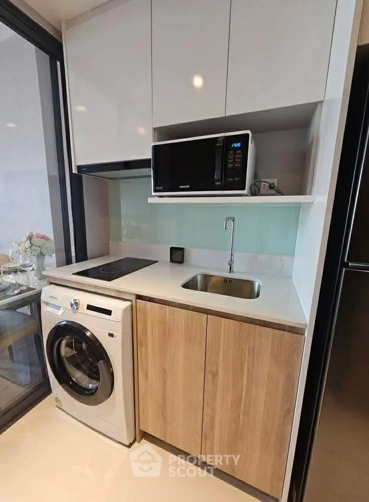 Modern compact kitchen with washing machine and microwave in sleek apartment