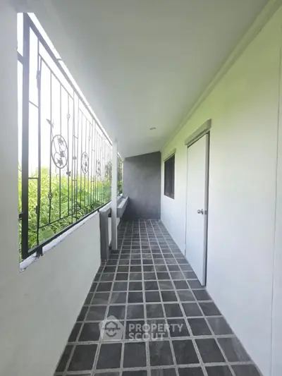 Spacious balcony with tiled flooring and garden view, perfect for relaxation.