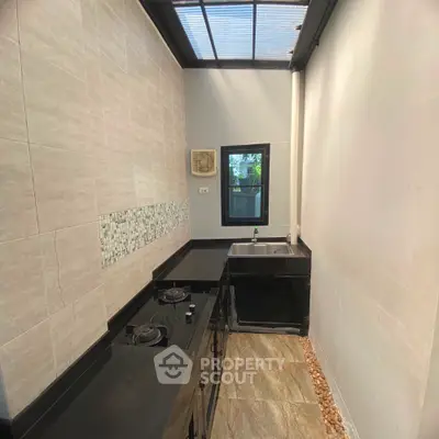 Modern kitchen with sleek black countertops and gas stove in a bright, airy space.