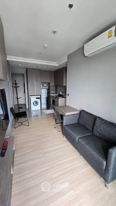 Modern living room with open kitchen, featuring sleek furniture and built-in appliances for urban living.