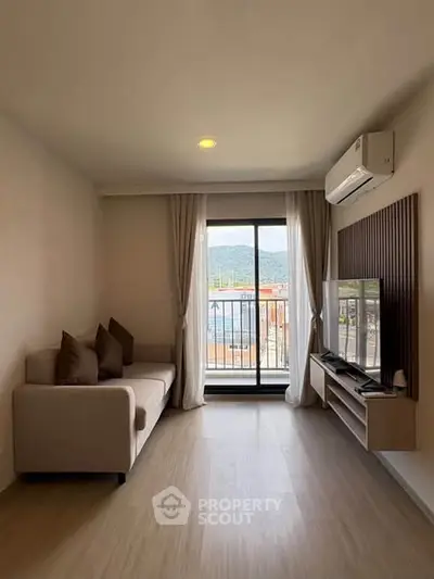 Modern living room with balcony view, featuring sleek furniture and air conditioning.